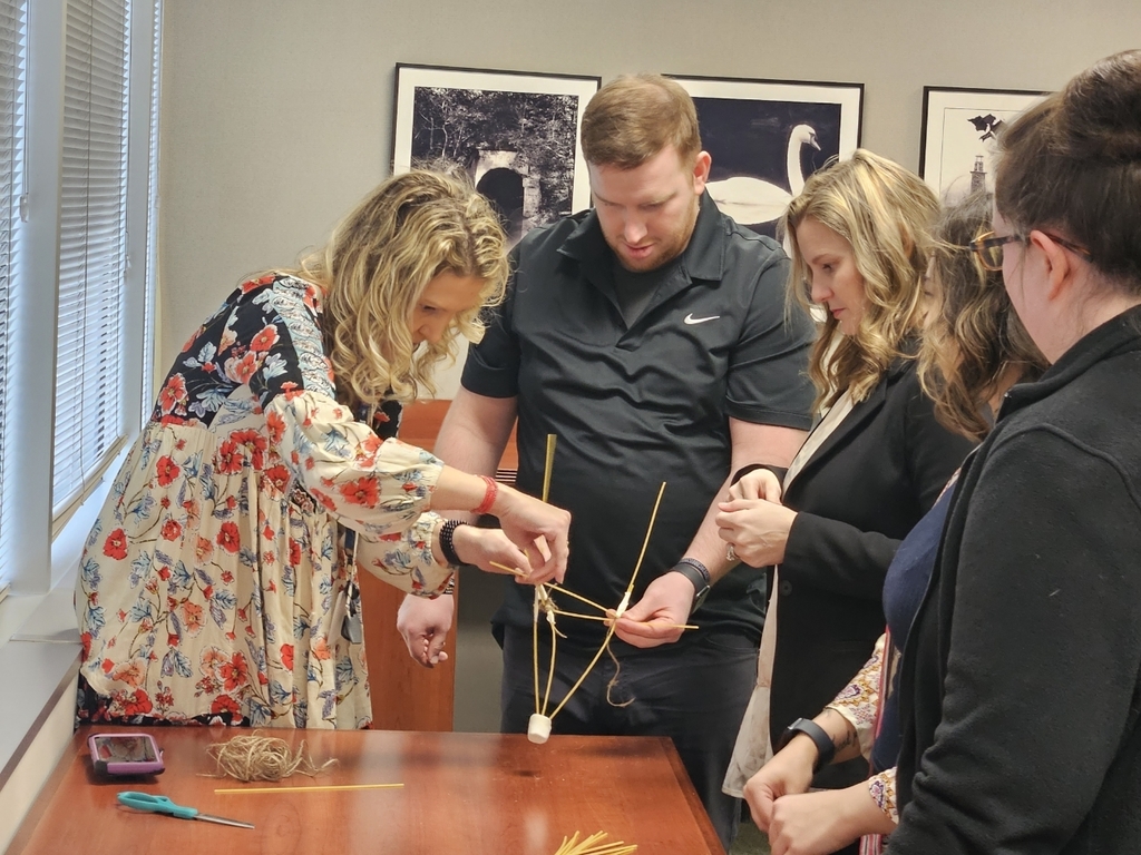 Teachers work together to build a structure. 